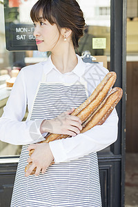 咖啡馆门口抱着新鲜出炉的法式面包的青年女性图片