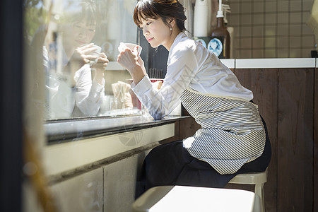 坐在窗边喝咖啡的年轻女性背景图片