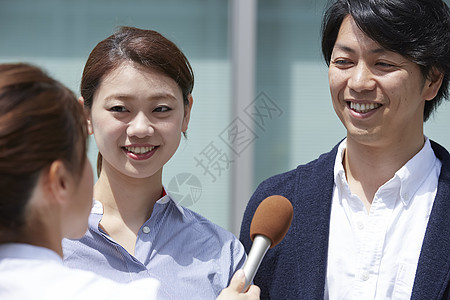 女记者开心街头采访一对夫妇背景图片