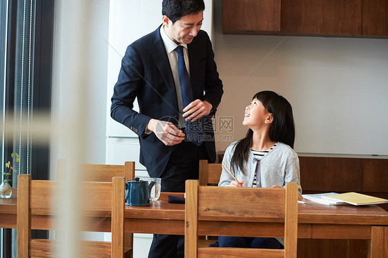 爸爸督促女儿在客厅写作业图片