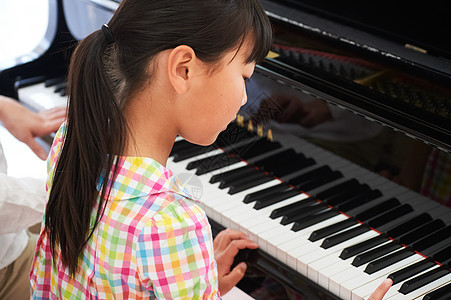 小女孩在家里学习钢琴课图片