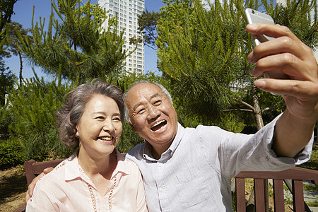 公园里拿着手机自拍的老年夫妇图片