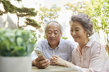 看着手机微笑的老年夫妇背景图片