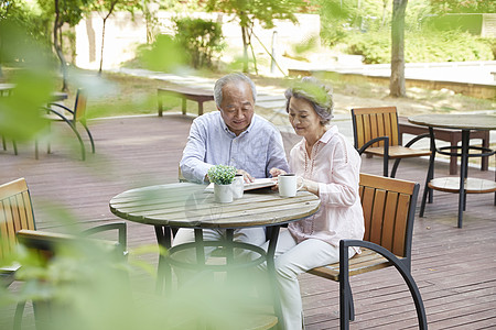 公园餐桌上看书的老年夫妇图片