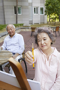 户外拿着画笔的老年女性图片