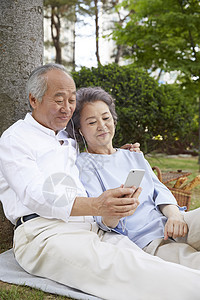 树下听音乐享受的老年夫妇图片