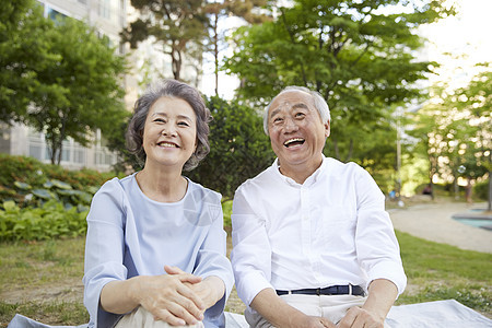 坐在楼下公园草坪上的老年夫妇图片