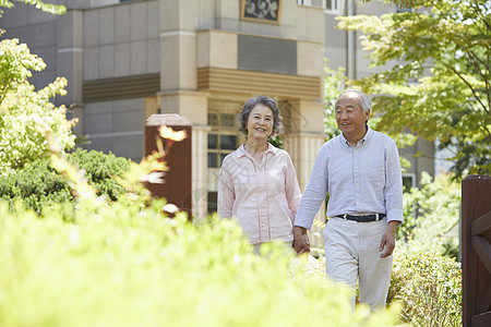 公园里手牵手散步的老年夫妇图片