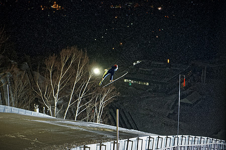 夜晚滑雪场跳跃滑翔的运动员图片