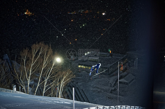 夜晚滑雪场跳跃滑翔的运动员图片