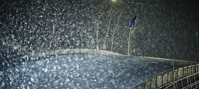 夜晚雪天滑雪场跳跃滑翔的运动员图片