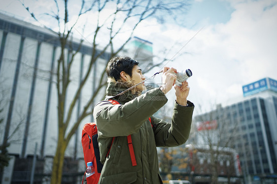 观光旅游拿着相机拍照的年轻人图片