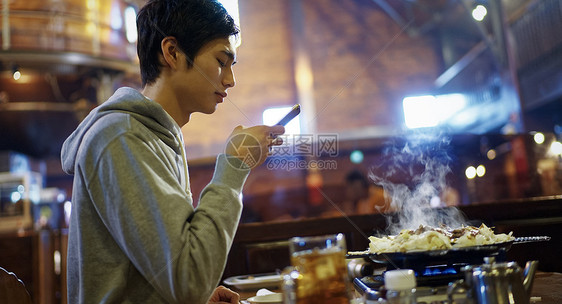 拿着手机拍摄食物照片的男性图片