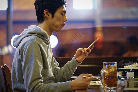 餐厅里看着手机的男性图片