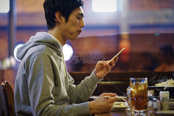 餐厅里看着手机的男性图片