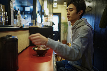 独自坐在拉面店吧台座位的男士图片