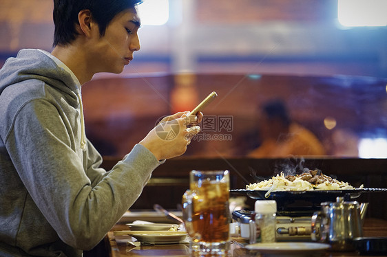 餐厅里拿着手机的男青年图片