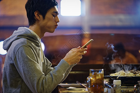 独自吃饭拿着手机的男青年图片