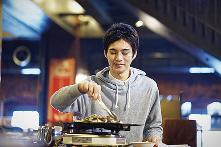 餐馆里独自烤肉的男青年图片