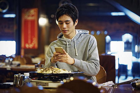 餐厅里拿着手机的青年男性图片
