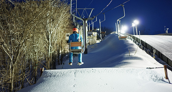 穿着滑雪服坐着缆车的运动员背影图片