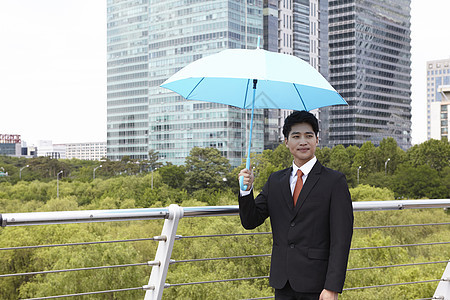 穿着西装举着雨伞的成年男子图片