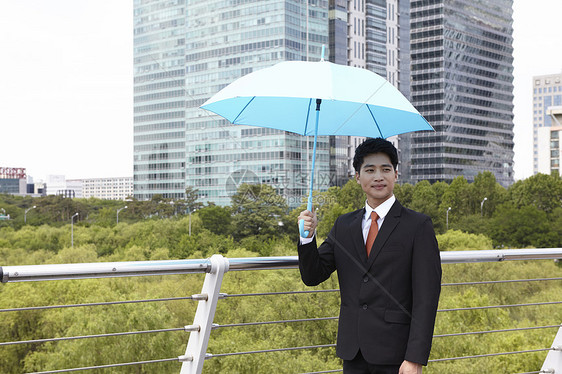 穿着西装举着雨伞的成年男子图片