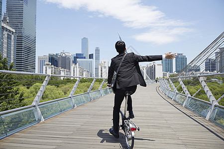 大桥上骑着自行车的成年男子背影图片