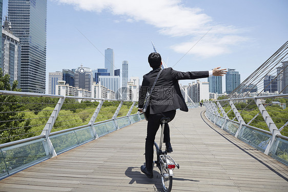 大桥上骑着自行车的成年男子背影图片