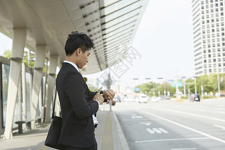 站在路边等车看手表的商务男性图片素材