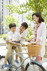 年轻父母陪着儿子骑自行车图片