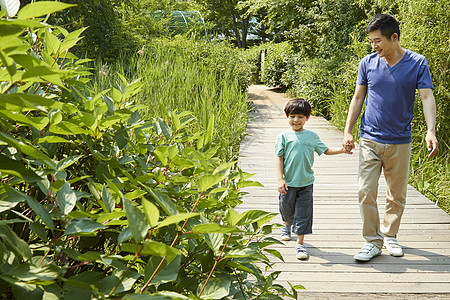 公园精神爸爸牵着儿子的手散步背景