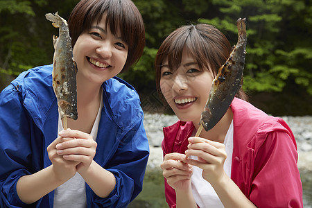 两个女人在河岸边放松享受烤鱼图片