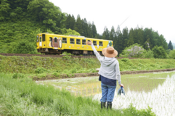 田间给路过汽车打招呼的农民图片