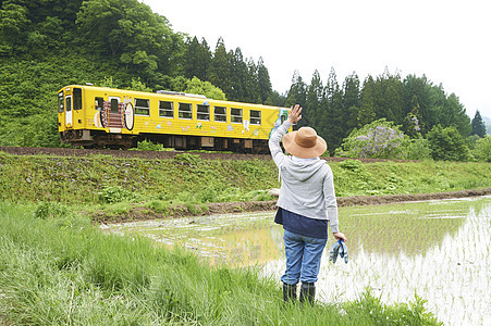 田间给路过汽车打招呼的农民图片