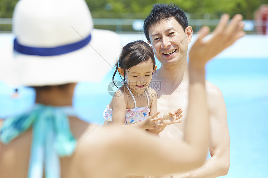 母亲向泳池里玩耍的父女打招呼图片