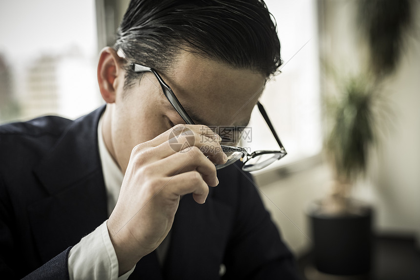 摘下眼镜的商务男性图片