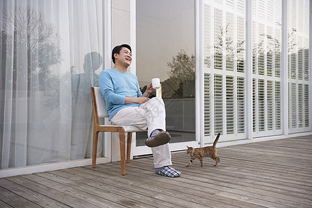 男子在门外坐在椅上喝咖啡休息图片