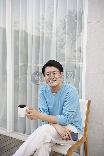 男子在门外坐在椅上喝咖啡休息图片