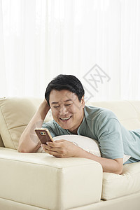 躺在沙发上玩手机的中年男人图片