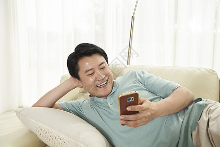 躺在沙发上玩手机的中年男人图片