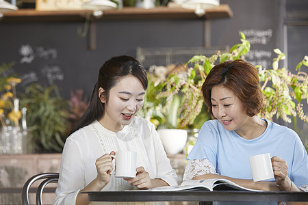 户外女儿开心的跟母亲喝咖啡看杂志图片