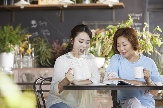 户外女儿开心的跟母亲喝咖啡看杂志图片