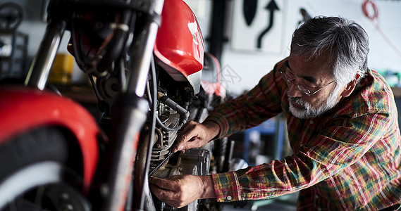 使用扳手修理摩托车的老人图片