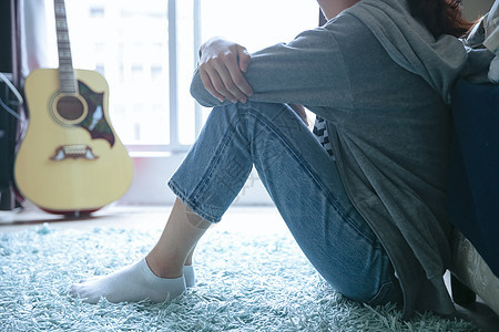 坐在地毯上的女孩和她的吉他图片