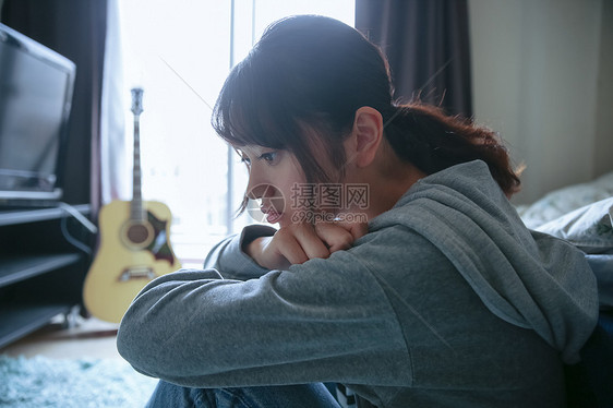 抱膝坐在地上发呆的漂亮女生图片