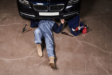 躺在地上维修汽车的机械师图片