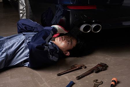维修汽车躺在地上的汽车维修师图片