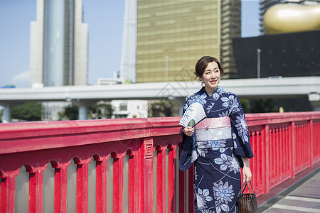 路上穿着和服拿着扇子微笑的年轻女性图片