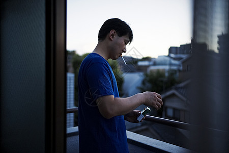 站在阳台抽烟的成年男性图片素材